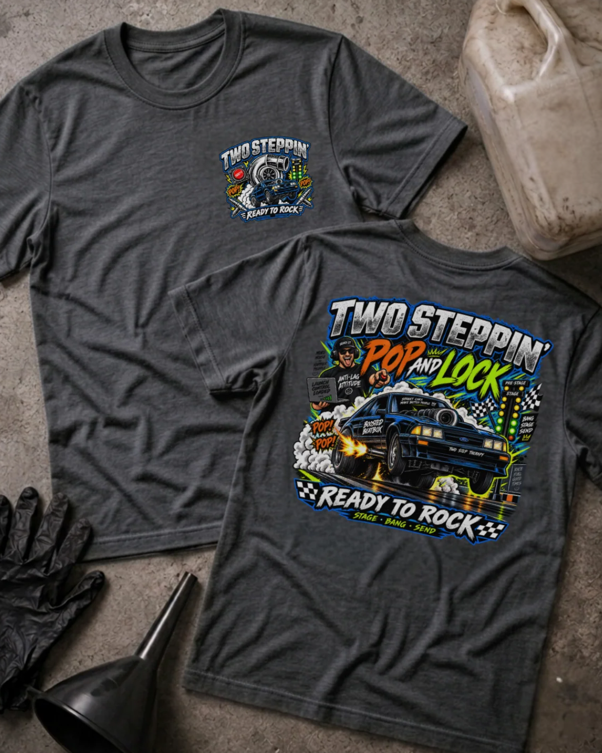 Front and back of Two-Step Pop and Lock dark grey heather T-shirt with chest logo, blue drag car launching amid smoke and flames, and “Two Steppin’ Pop and Lock, Ready to Rock” text.