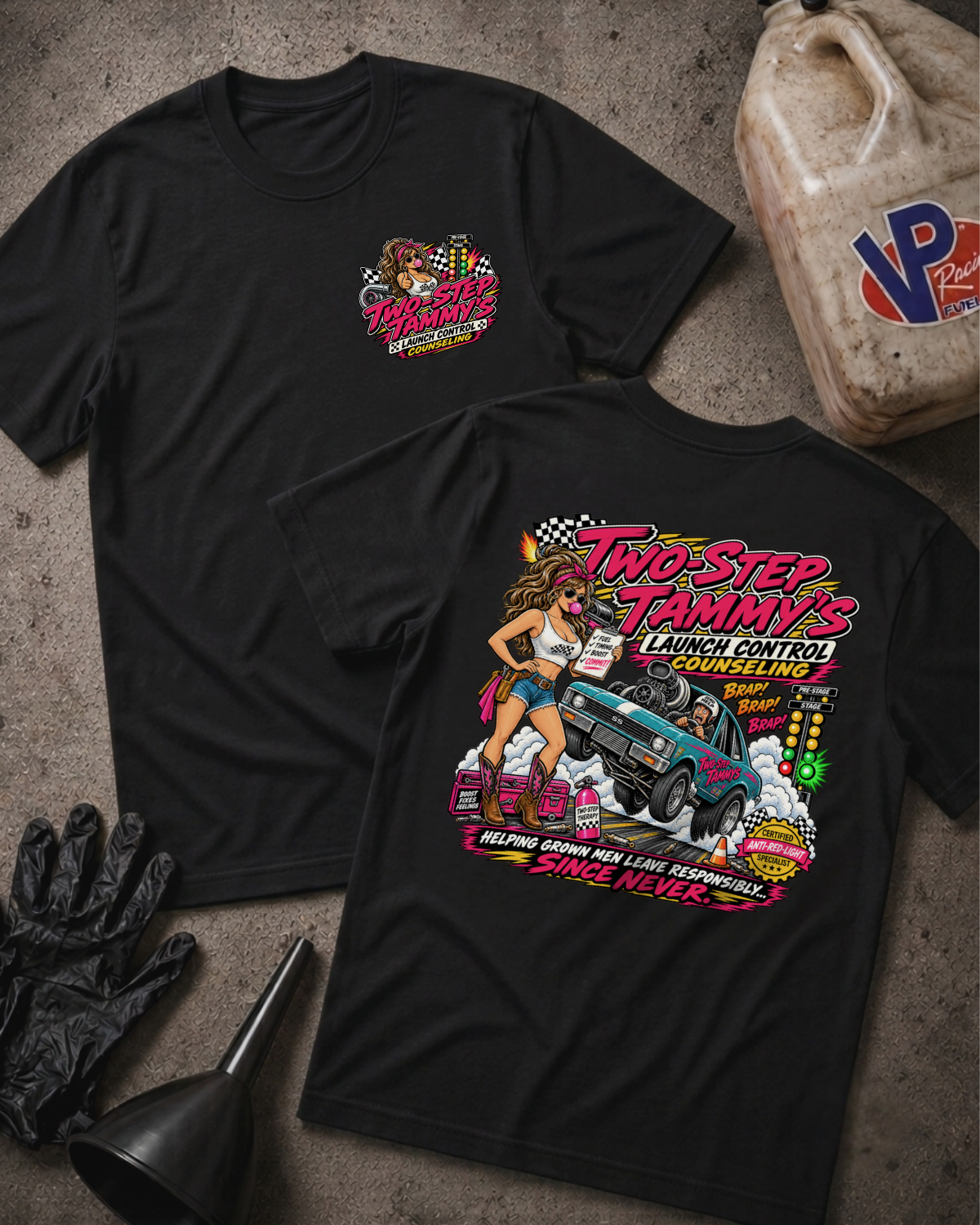 Two black graphic T-shirts laid flat on a textured concrete surface, showing front and back designs. The front has a small 'Two-Step Tammy's Launch Control Counseling' chest logo, and the back has a large colorful illustration with a woman, a drag car doing a burnout, and the text 'Helping grown men leave responsibly... since never.'