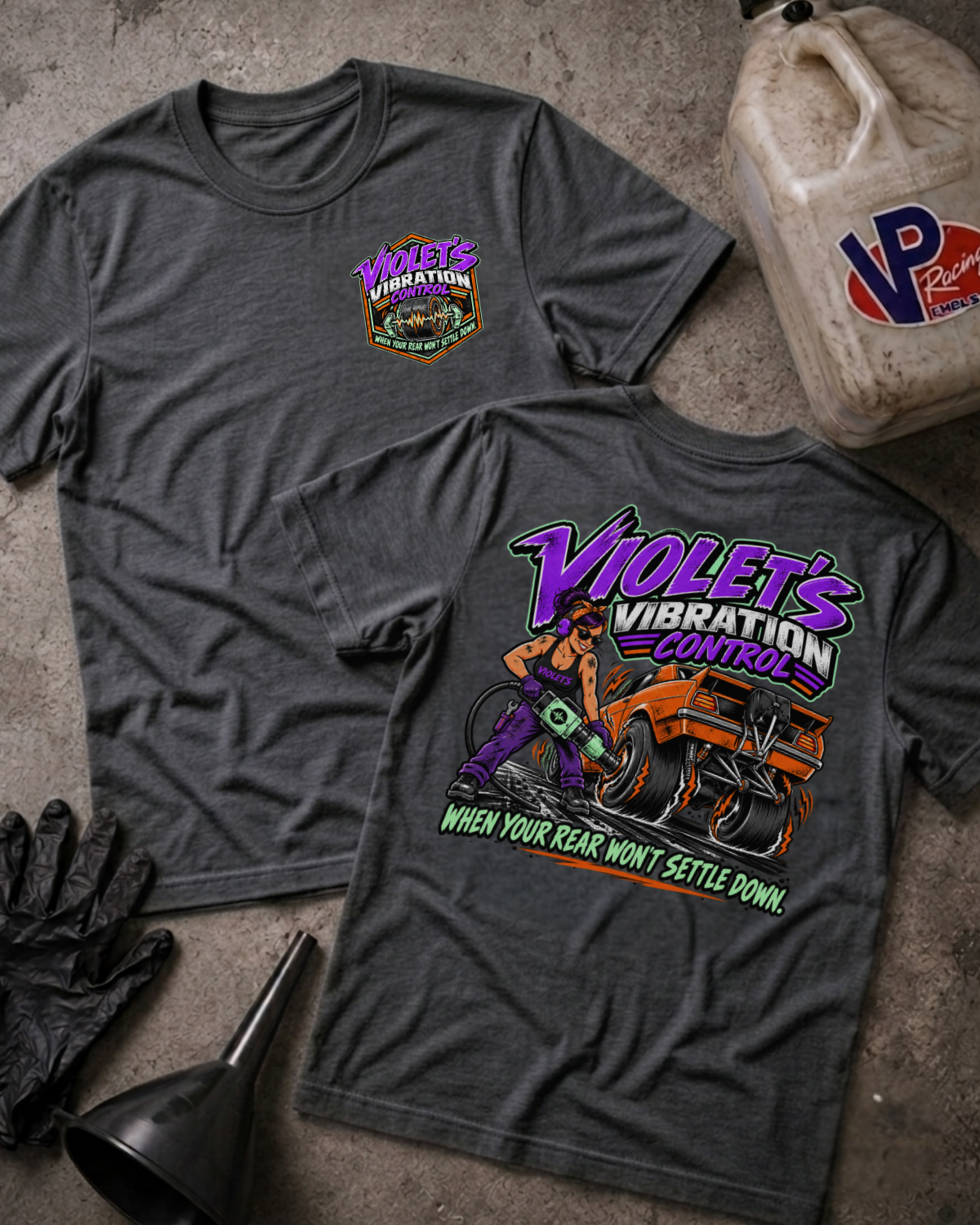 Two dark grey heather graphic t-shirts showing a 'VIOLET'S VIBRATION CONTROL' logo on the front and a colorful graphic of a woman and a racecar with 'VIOLET'S VIBRATION CONTROL WHEN YOUR REAR WON'T SETTLE DOWN' text on the back