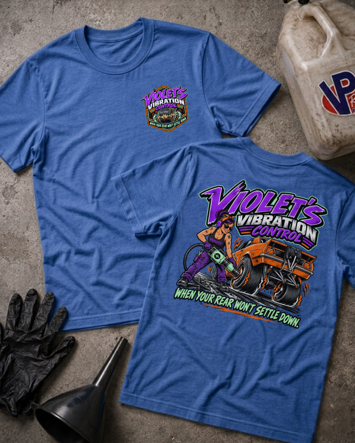 Two heather true royal graphic t-shirts showing a 'VIOLET'S VIBRATION CONTROL' logo on the front and a colorful graphic of a woman and a racecar with 'VIOLET'S VIBRATION CONTROL WHEN YOUR REAR WON'T SETTLE DOWN' text on the back