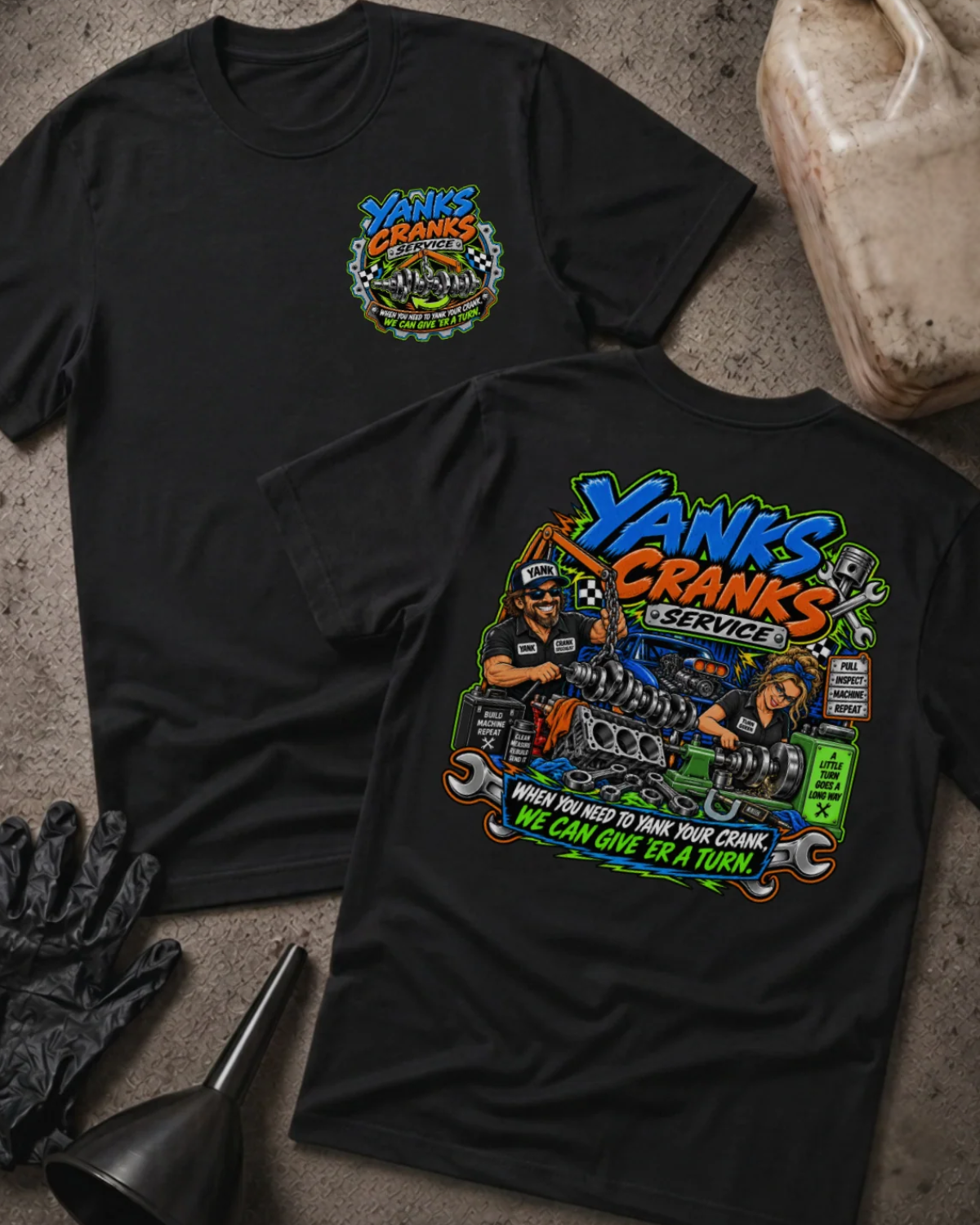 Front and back of Yank’s Cranks Service black T-shirt with chest logo, two mechanics working on crankshafts, and “When you need to yank your crank, we can give ’er a turn” slogan.