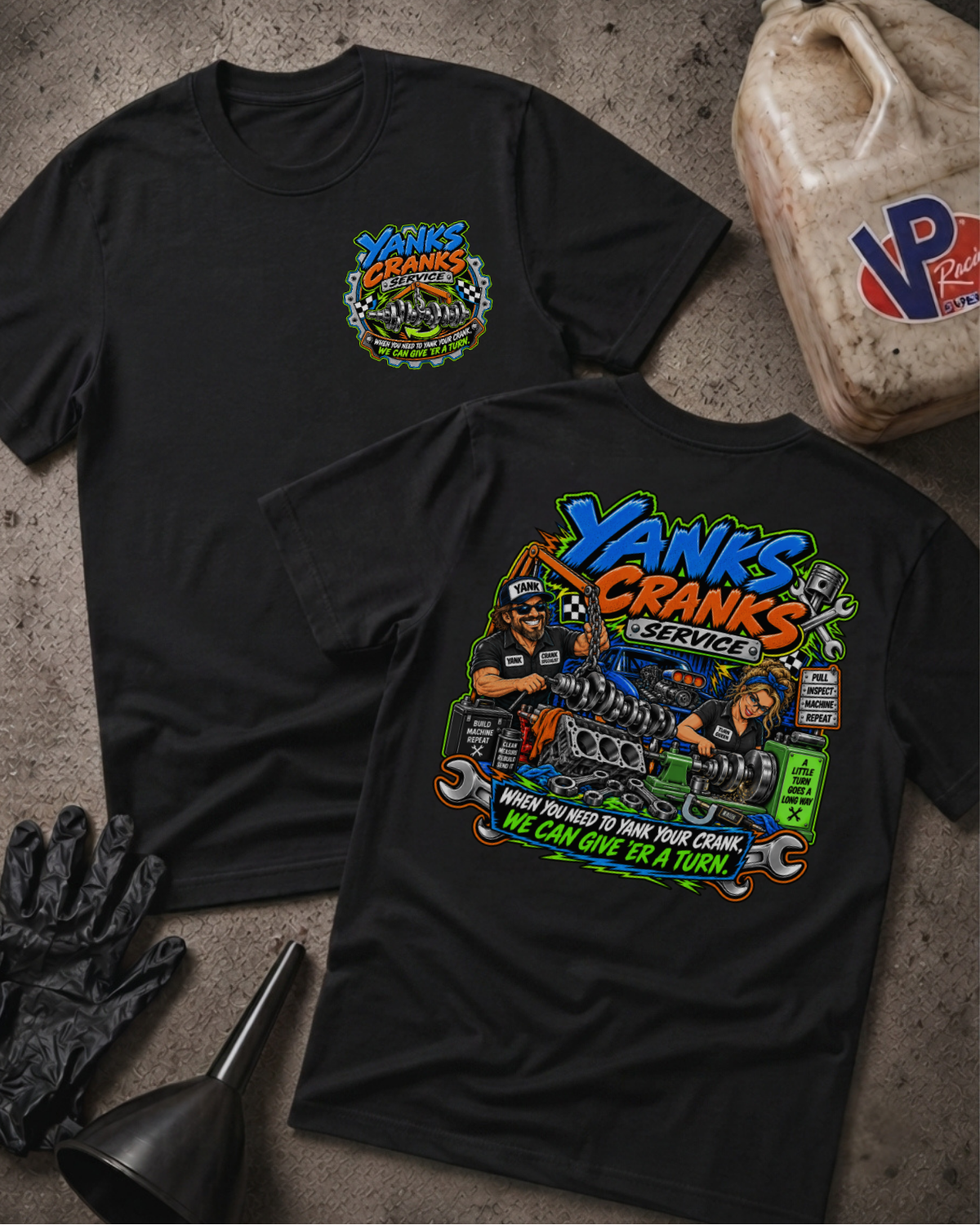 Two black graphic T-shirts laid flat on a textured gray surface, showing the front and back designs. The shirts feature a colorful 'Yanks Crank Service' engine illustration and text.