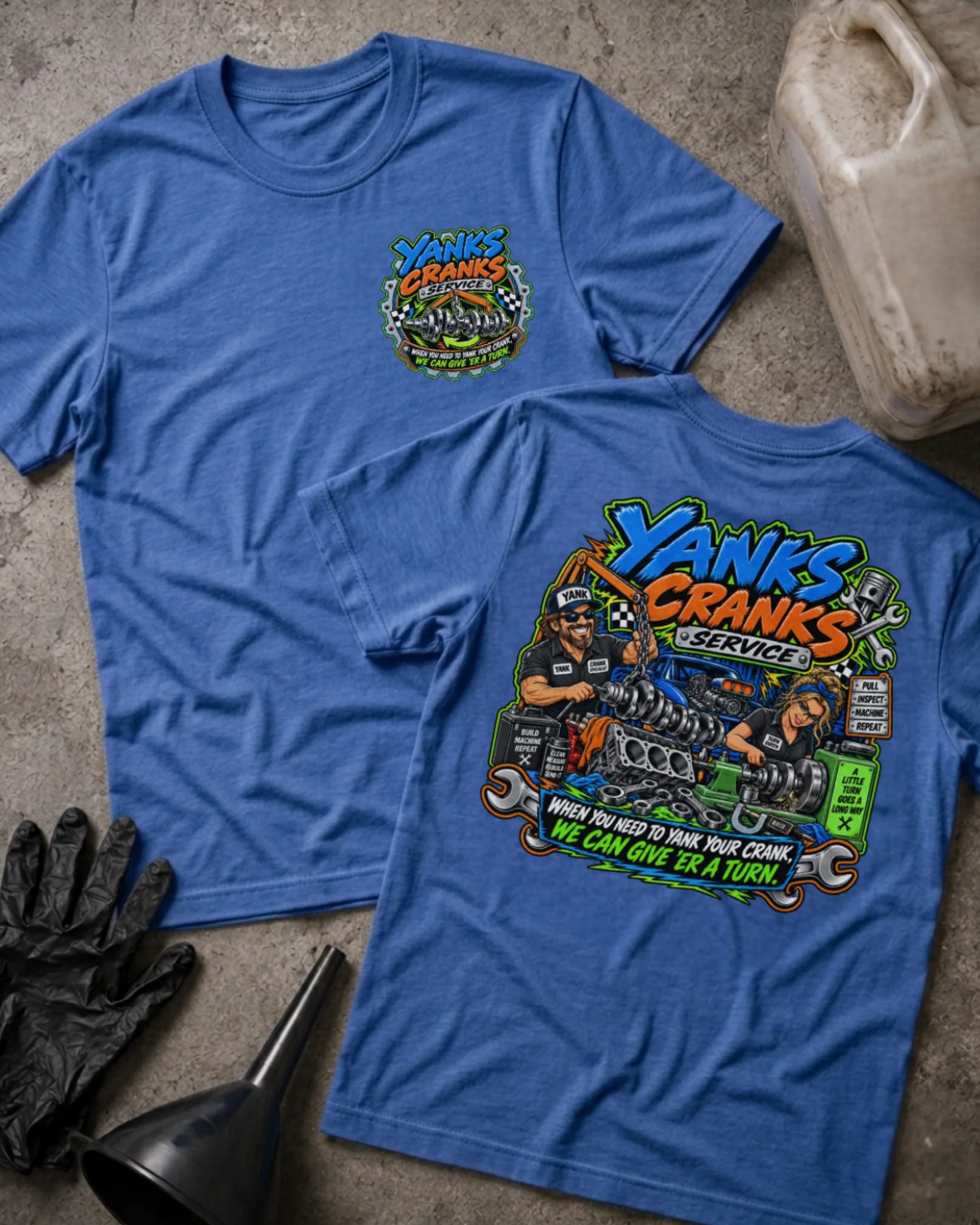 Front and back of Yank’s Cranks Service heather true royal T-shirt with chest logo, two mechanics working on crankshafts, and “When you need to yank your crank, we can give ’er a turn” slogan.